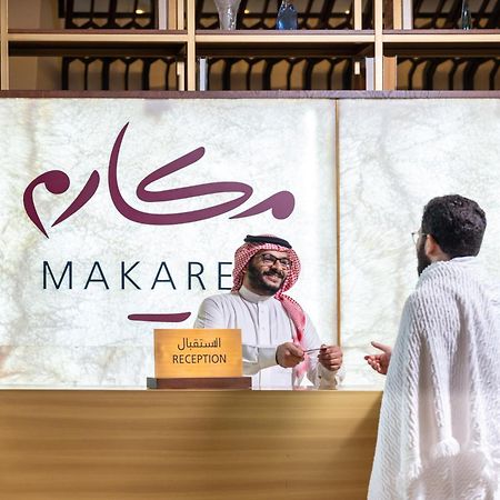 Makarem Ajyad Makkah Hotel Mekka Zewnętrze zdjęcie The photo depicts a reception area in a hotel or establishment named "Makarem." In the image, a receptionist, dressed in traditional attire, is smiling and interacting with a guest who is wearing a white robe, commonly known as a thobe or ihram. The 