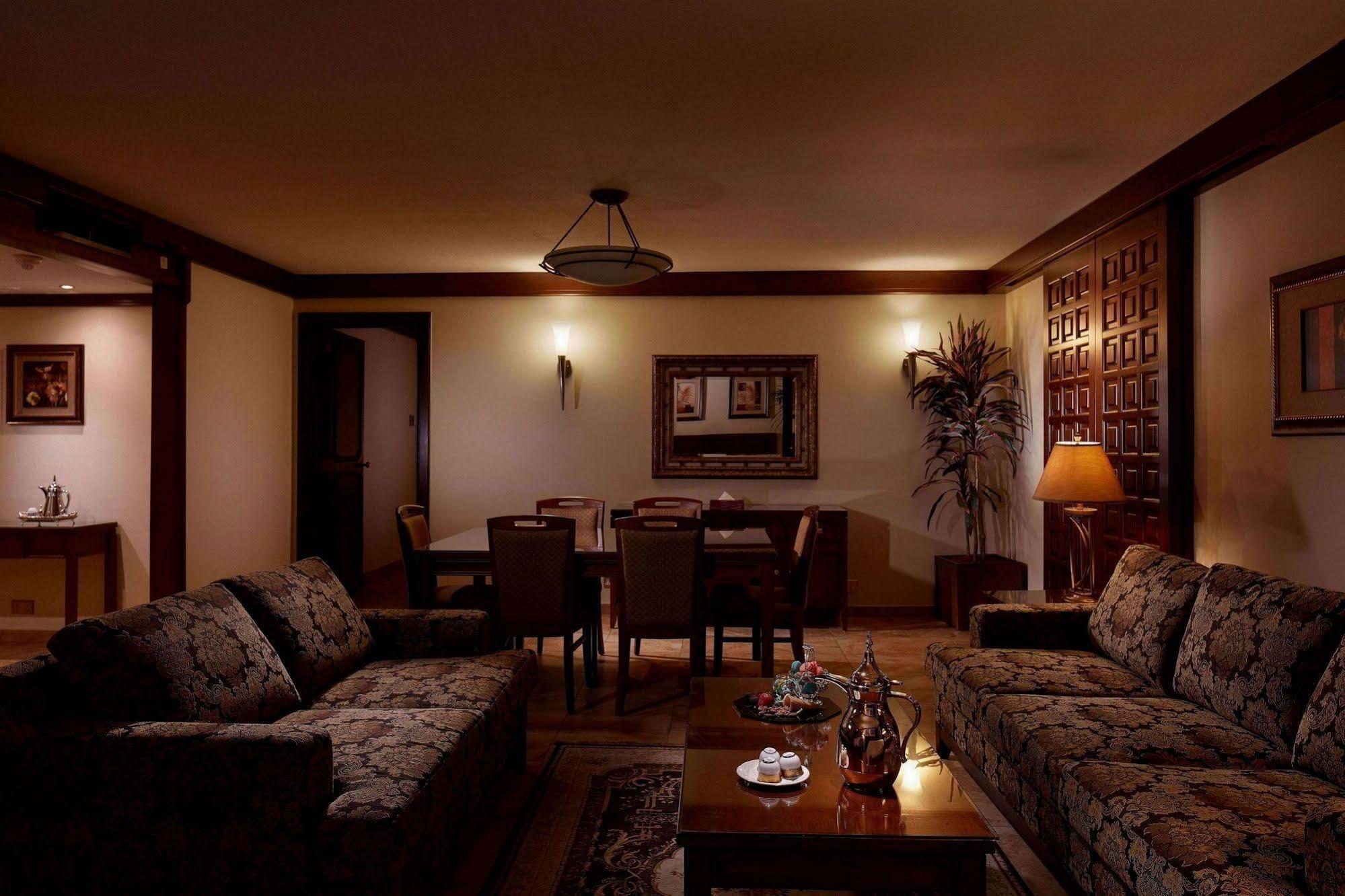 Makarem Ajyad Makkah Hotel Mekka Zewnętrze zdjęcie The photo depicts a cozy living room setting. It features two patterned sofas facing each other with a wooden coffee table in the center. The room is softly illuminated, creating a warm atmosphere. On the walls, there are decorative elements, includi