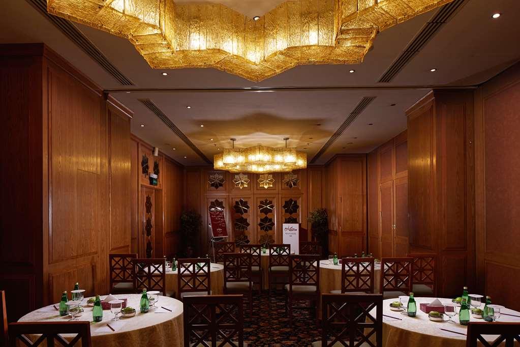 Makarem Ajyad Makkah Hotel Mekka Udogodnienia zdjęcie The photo shows a well-decorated dining room with wooden paneling and elegant furnishings. There are round tables covered with tablecloths, and each table is arranged with glasses of water. The lighting is warm, provided by elaborate chandeliers on t