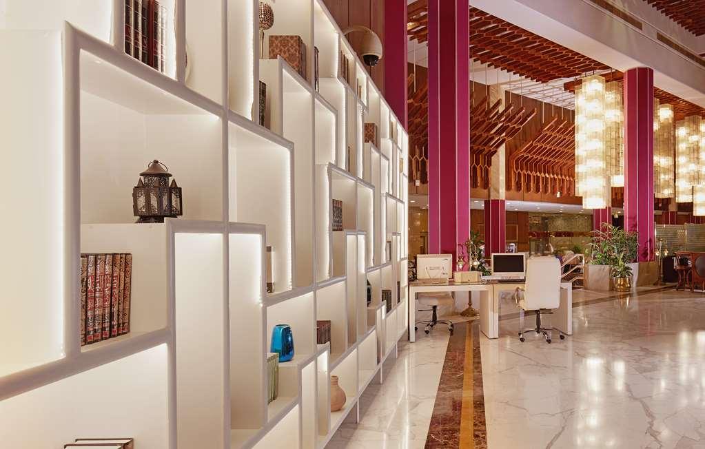 Makarem Ajyad Makkah Hotel Mekka Wnętrze zdjęcie The photo shows a modern interior space, likely a lobby or lounge area of a stylish hotel or building. There is a partition wall made up of white shelving units illuminated from within, displaying various decorative items, books, and vases. The desig