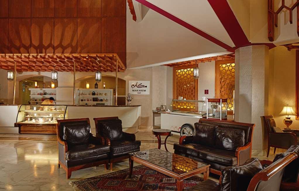 Makarem Ajyad Makkah Hotel Mekka Wnętrze zdjęcie The photo shows a stylish interior of a lobby or lounge area. It features a seating arrangement with dark leather armchairs and a wooden table in front of them. The decor includes an intricate ceiling design and decorative wall elements that add a wa