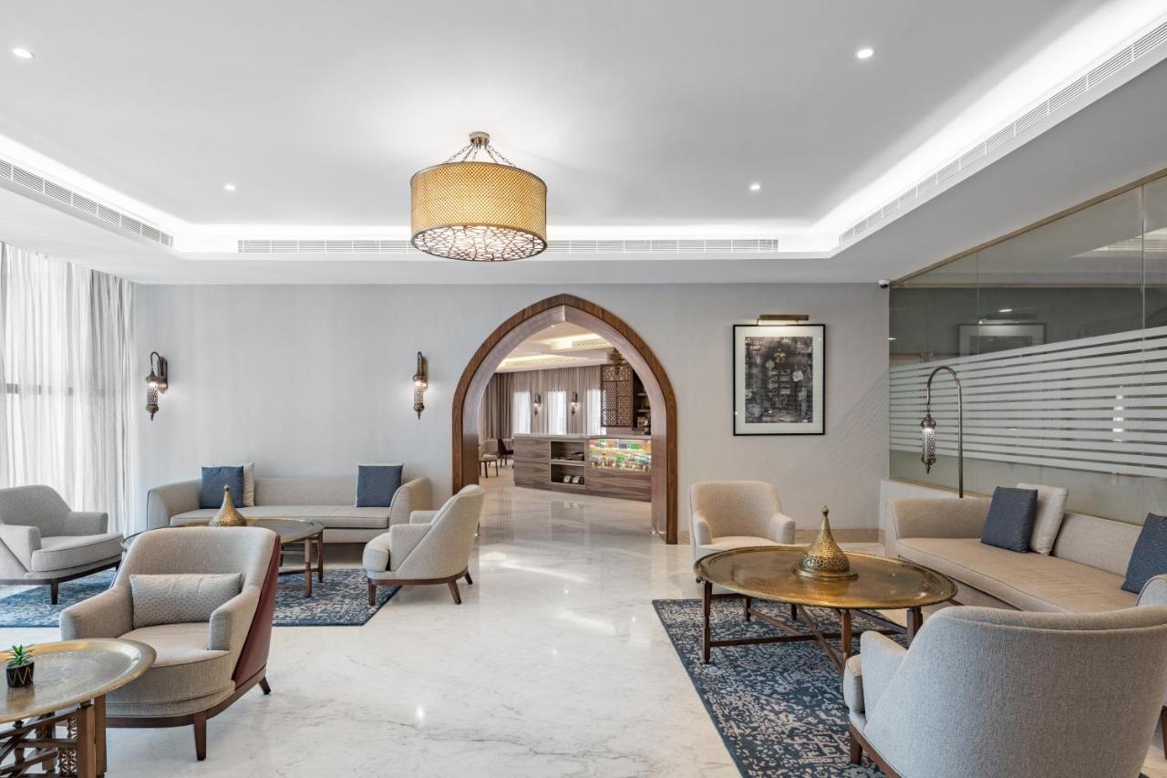Makarem Ajyad Makkah Hotel Mekka Zewnętrze zdjęcie The photo shows a modern and elegantly designed lounge area. It features light-colored walls and marble flooring, complemented by stylish furniture including several armchairs and small tables. The lighting is soft, provided by a decorative chandelie