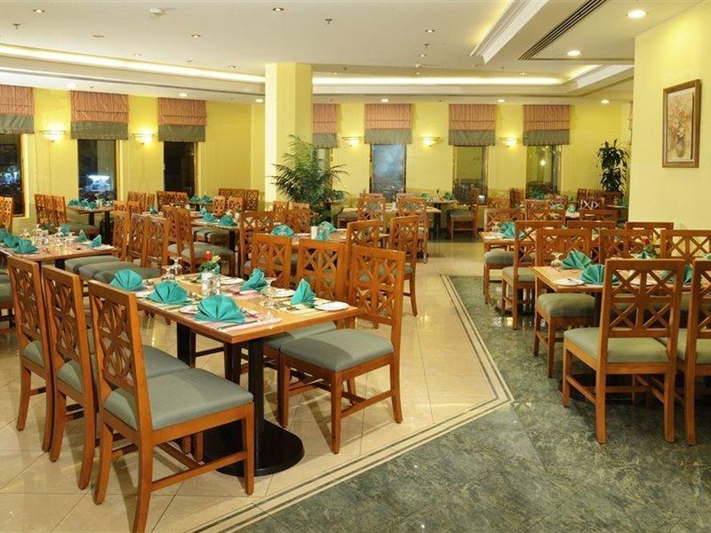 Makarem Ajyad Makkah Hotel Mekka Zewnętrze zdjęcie The photo shows an interior view of a restaurant. It features wooden tables and chairs arranged neatly throughout the space. Each table is set with turquoise napkins, contributing to the overall decor. The walls are painted a soft yellow, and there a