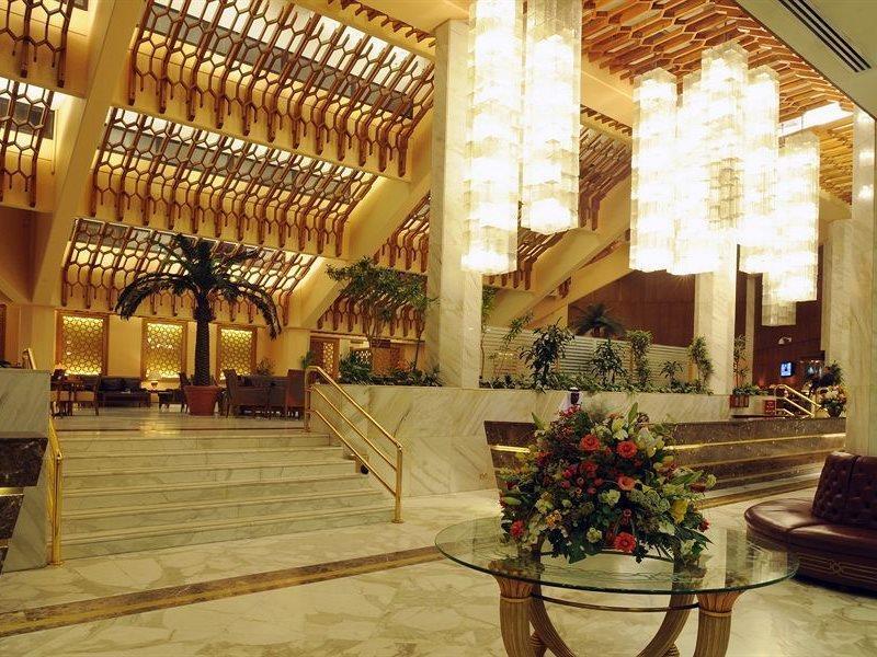 Makarem Ajyad Makkah Hotel Mekka Zewnętrze zdjęcie The photo shows a luxurious hotel lobby with elegant design features. It has high ceilings adorned with wooden beams and large, decorative light fixtures hanging from above. The lobby is brightly lit, creating a warm and inviting atmosphere. There ar