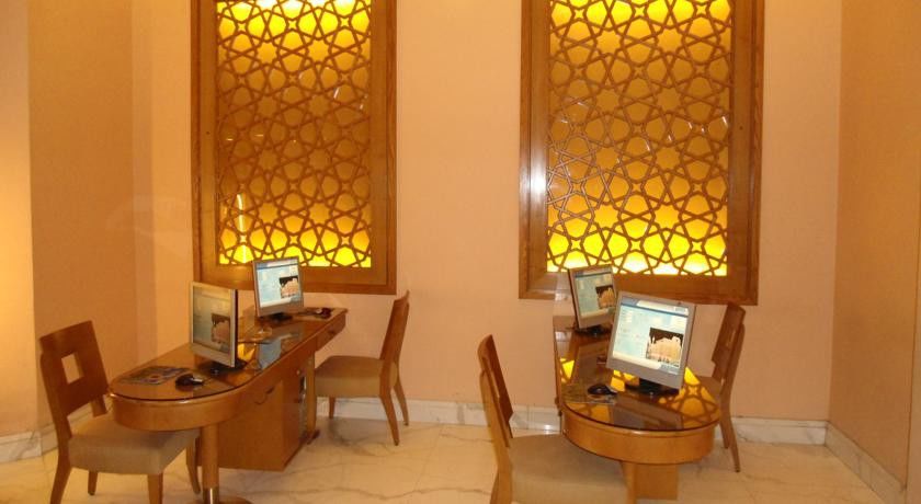 Makarem Ajyad Makkah Hotel Mekka Zewnętrze zdjęcie The image shows a room with a warm, inviting atmosphere, featuring two wooden desks equipped with computers. Each desk has a chair positioned in front of it. The walls are adorned with decorative panels that exhibit intricate patterns, illuminated by